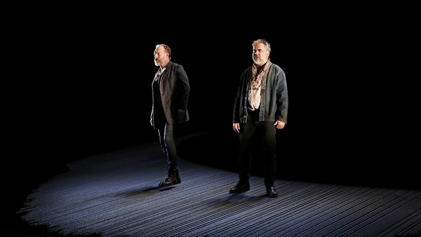 Hugo Weaving (left) and Wayne Blair (right) lit up on an empty stage, surrounded by darkness.