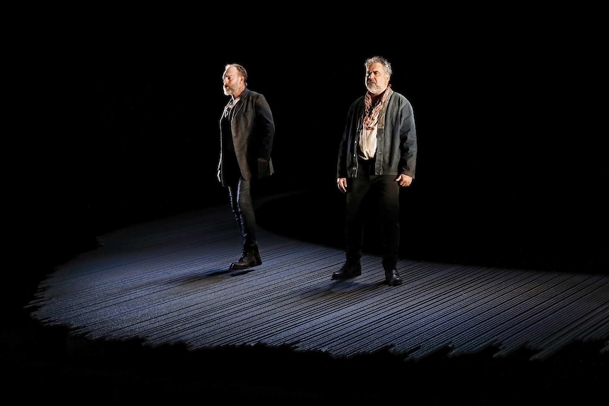 Hugo Weaving (left) and Wayne Blair (right) lit up on an empty stage, surrounded by darkness.