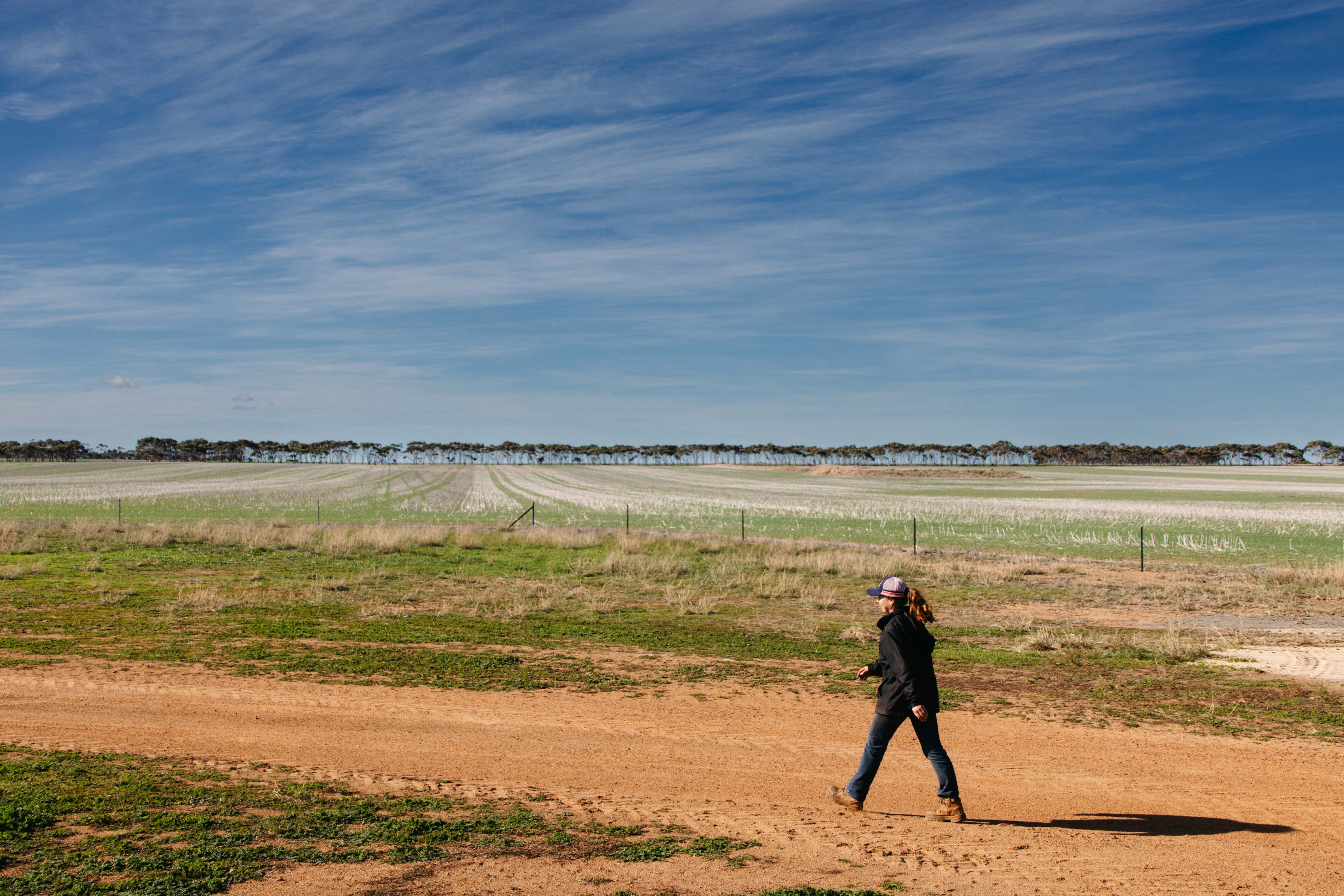 A young woman walking along a dirt road at a farm in WA.
