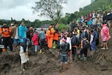 People gather around the site of a landslide.