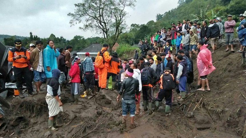 People gather around the site of a landslide.