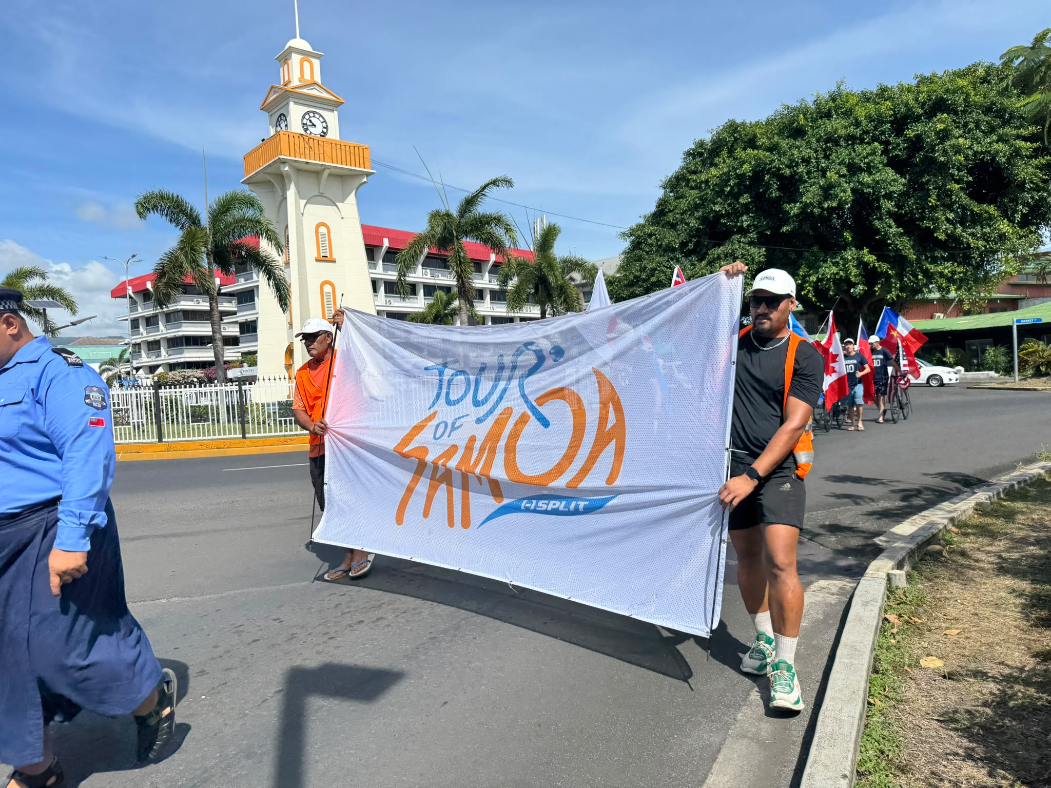 People holding a banner march around a clock tower roundabout in Apia, Samoa 