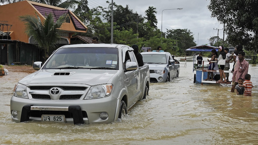 Local residents drive through floodwaters in Narathiwat province