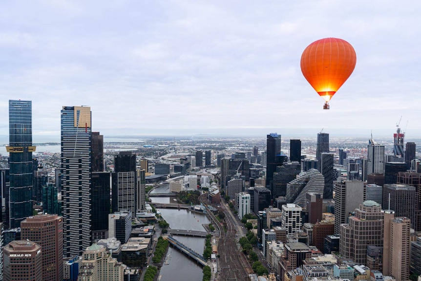 An orange balloon flies over Melbourne with the Yarra River in the background