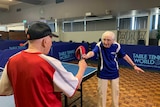 Two elderly male table tennis players touch paddles after playing a game