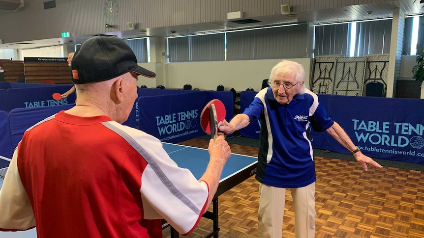 Two elderly male table tennis players touch paddles after playing a game