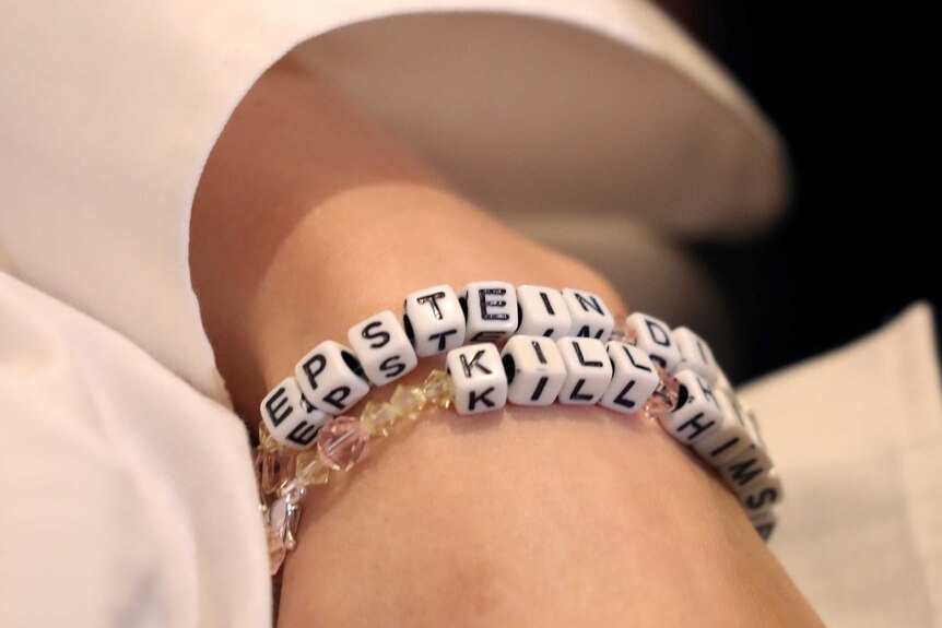 A close-up of a bracelet reading 'Epstein didn't kill himself'