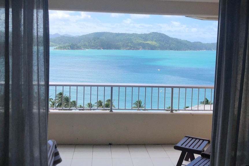 A view from a bedroom overlooking a balcony and the ocean. 