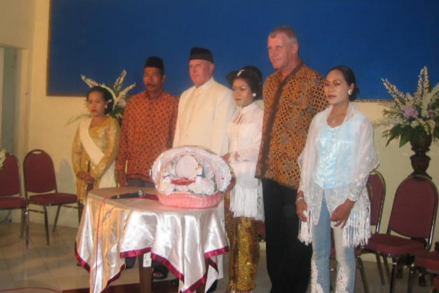 A group of people standing next to each other in a wedding.