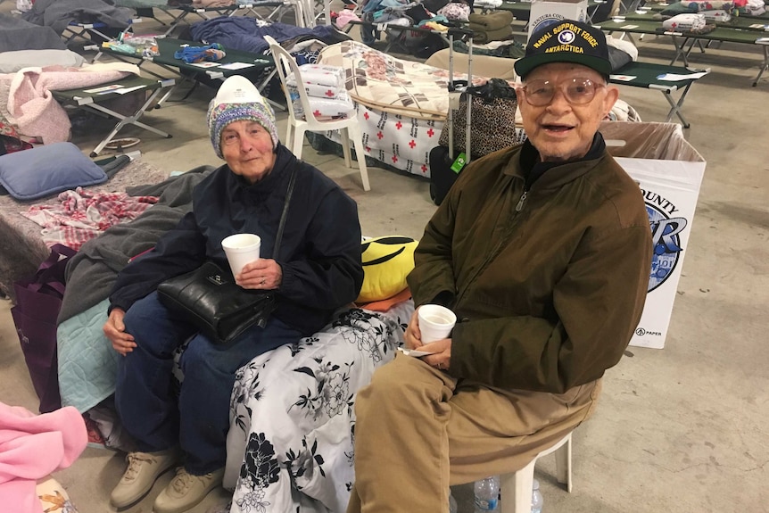 Elderly couple sit in shelter with holding cups