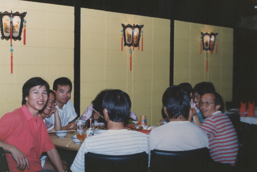 A group of diners smiling at the table of a Chinese restaurant and laughing.