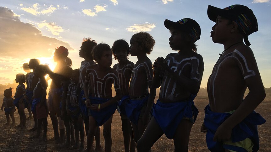 Gurindji children wearing traditional costume stand in a line.