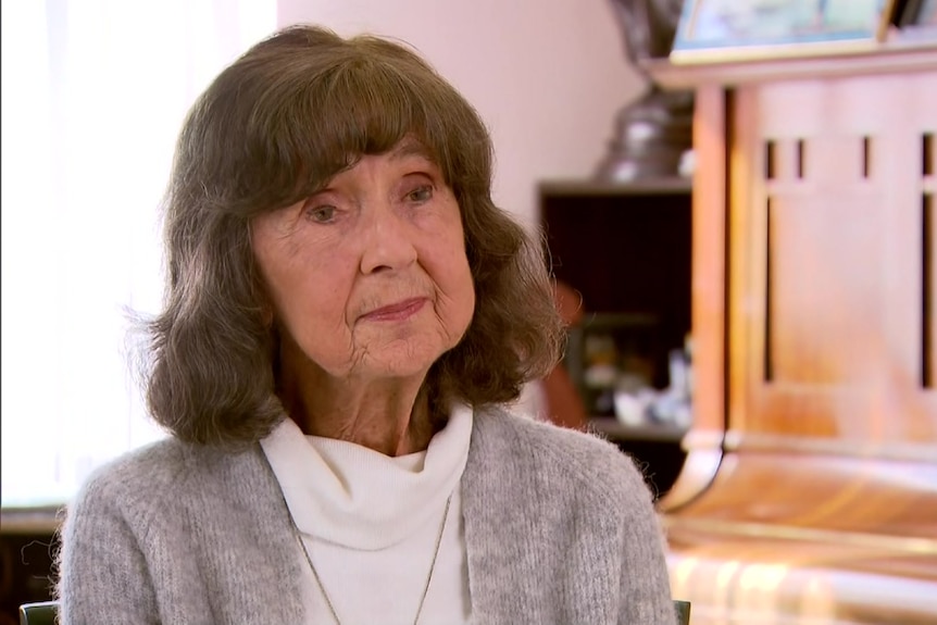 a woman with brown hair and a gray cardigan.