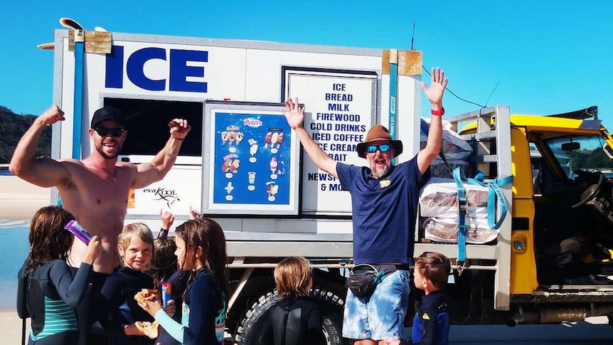Two men standing in front of an ice truck.