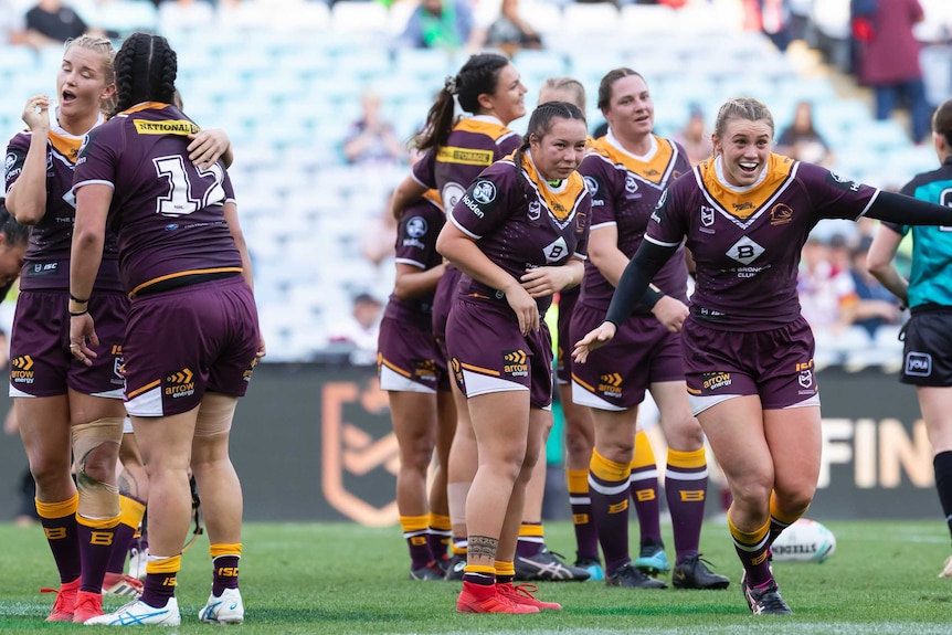 A group of excited NRLW players run towards teammates after winning the grand final.