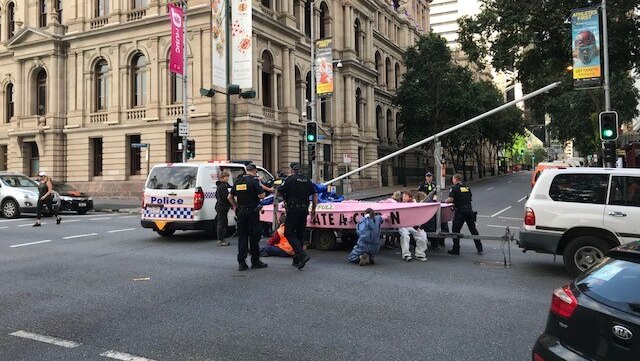 Extinction Rebellion  protesters locked onto pink cataraman with police officers around.