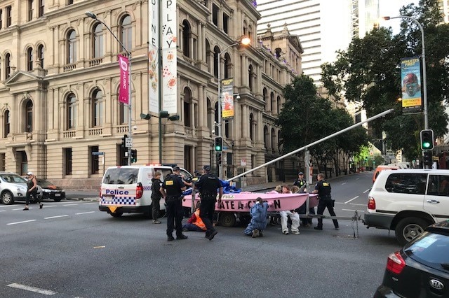 Extinction Rebellion  protesters locked onto pink cataraman with police officers around.