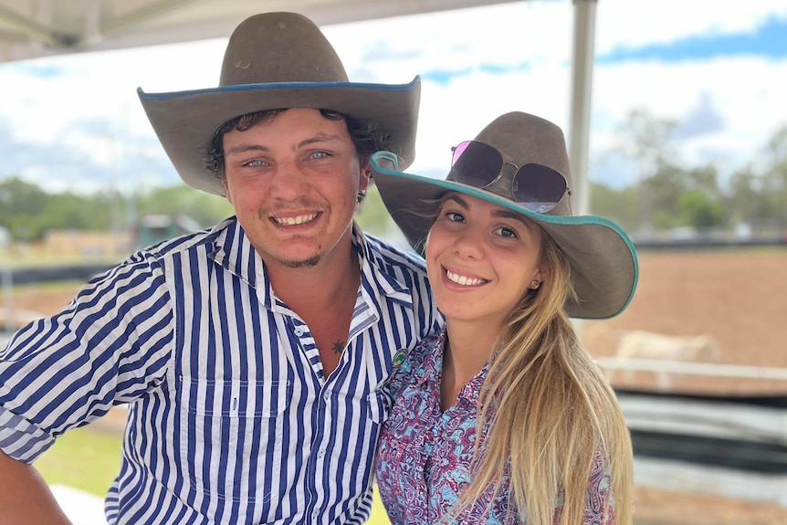 Man and woman smile at camera wearing wide brim country hats. 