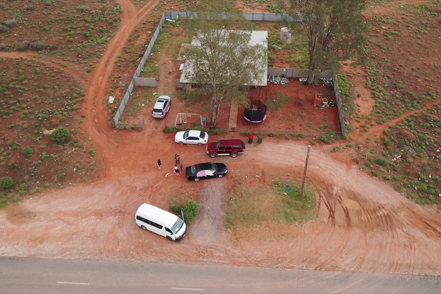 An aerial view of a home on it's own surrounded by red dirt and bush.