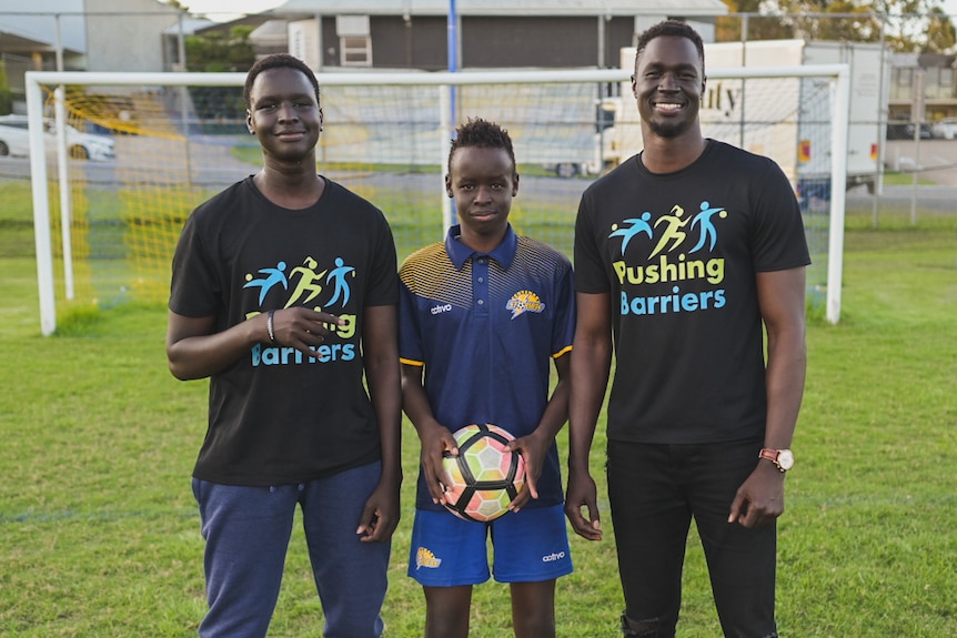 The brothers standing in front of a soccer goal. 