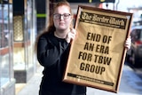 A young woman stands holding a large framed front page of The Border Watch headlined 'End of an era for TBW Group'.