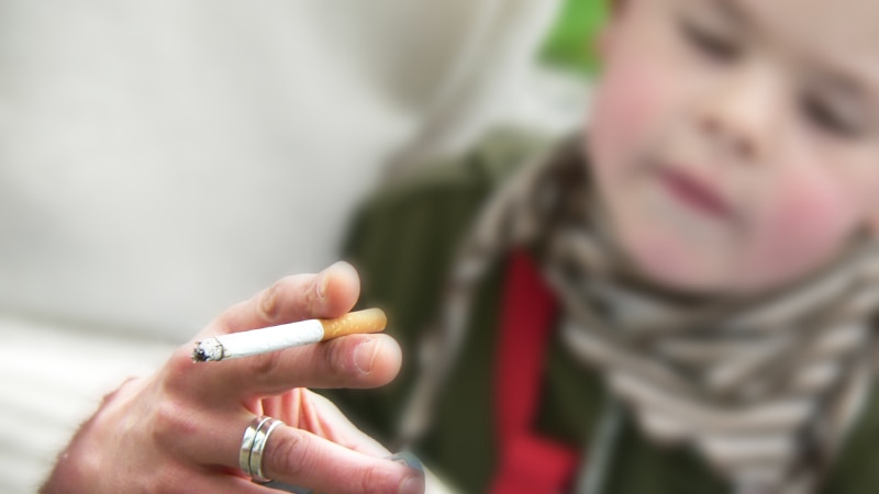 A close up shot of a cigarette with a child in the background