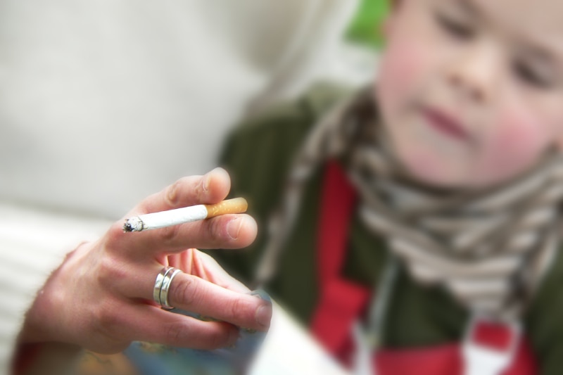 A close up shot of a cigarette with a child in the background