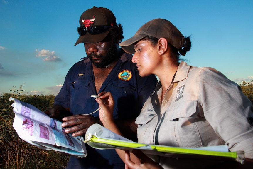 A man looks at notes while a woman holds a lizard.