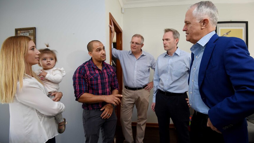 Malcolm Turnbull (right) with Scott Morrison (centre) talking to a Sydney couple with their 11 month old daughter in their home.