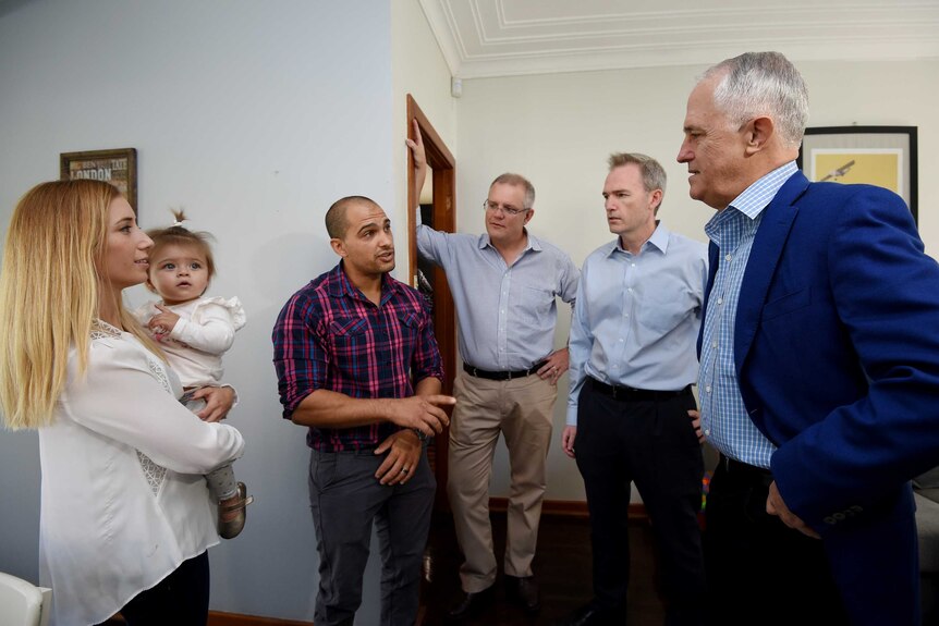 Malcolm Turnbull (right) with Scott Morrison (centre) talking to a Sydney couple with their 11 month old daughter in their home.