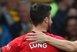 Shane Long wearing the number seven shirt with his back to the camera, holds his hands out wide as he is hugged by two teammates