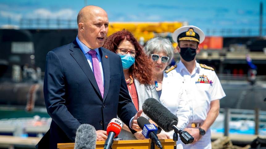 Peter Dutton addresses the media from a naval vessel. 