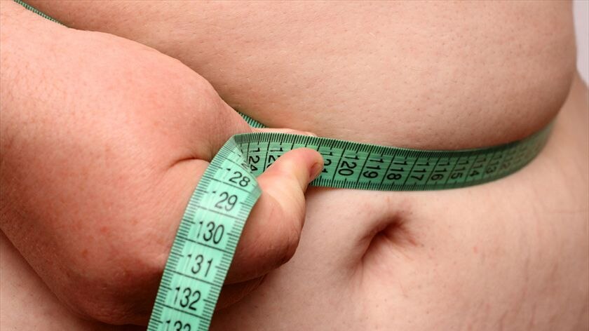 An obese stomach with a measuring tape around it.