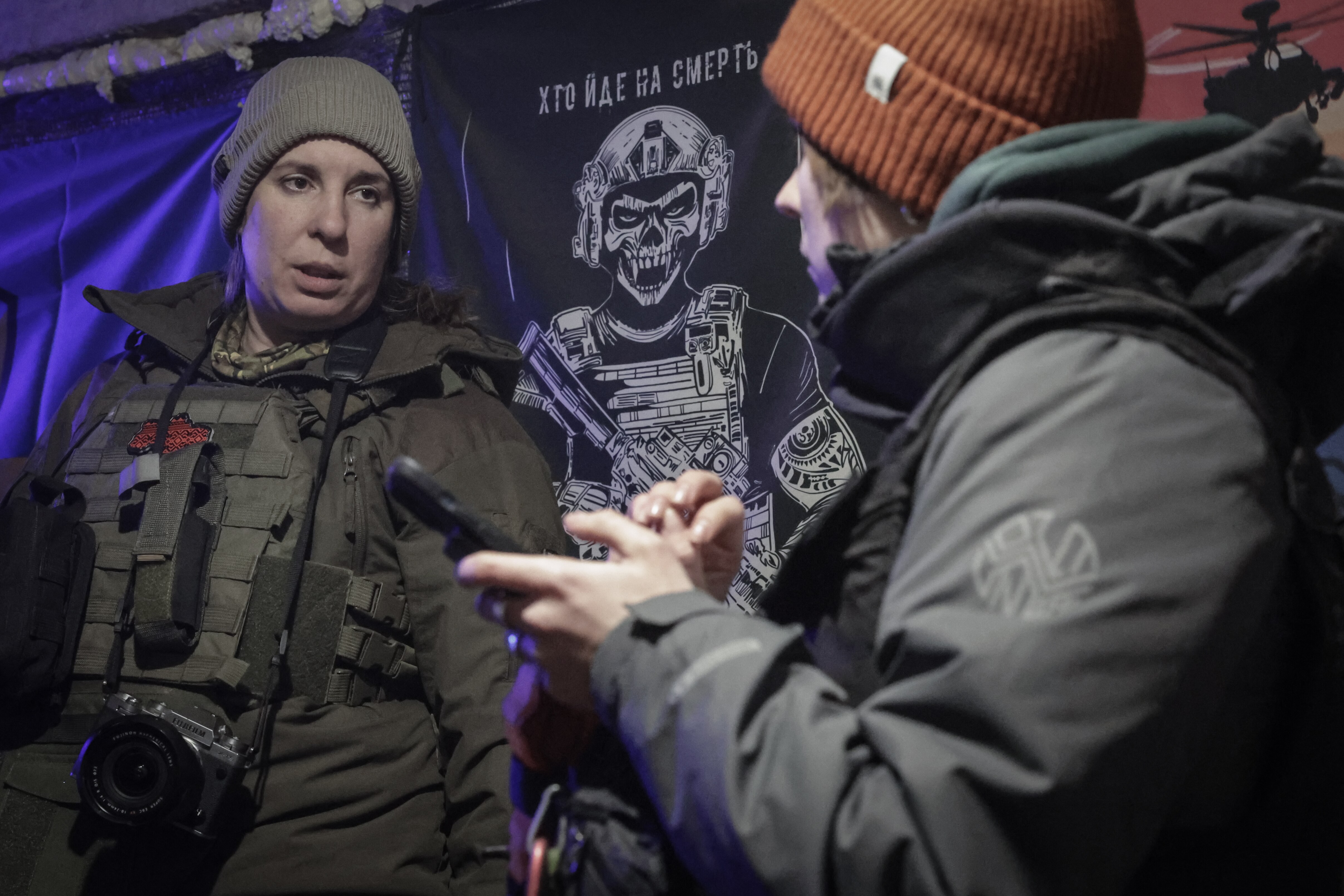 Two women in front of a banner of a skeleton.