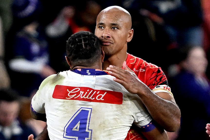 Dolphins player Felise Kaufusi hugs Melbourne Storm player Justin Olam after an NRL game.