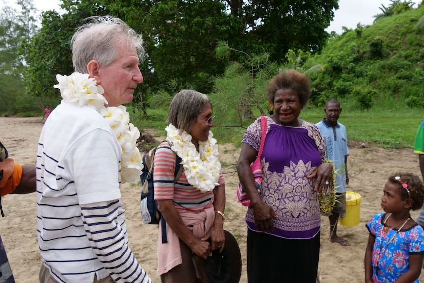 Dorney and wife with floral leis around necks being greeted by locals.