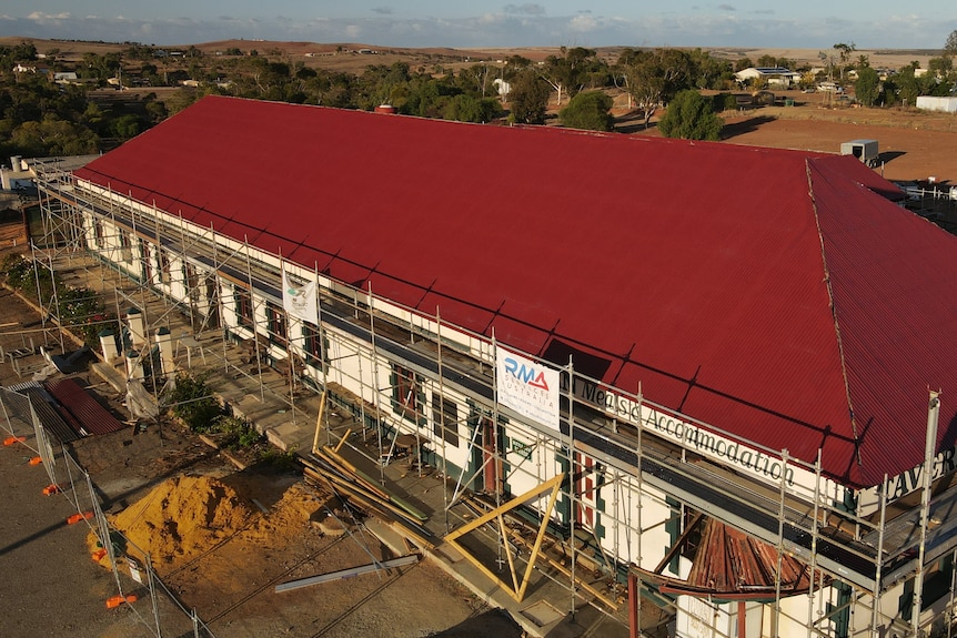 Old building surrounded by scaffolding with long red iron roof 