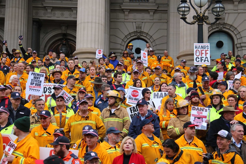 Hundred of CFA volunteers in yellow uniforms at a protest.