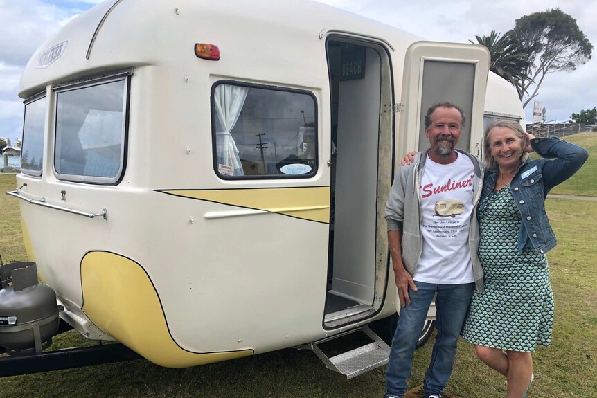 Walter and Adrienne Hacene standing arm in arm outside one of their three Sunliner caravan at the 60th Anniversary in Forster