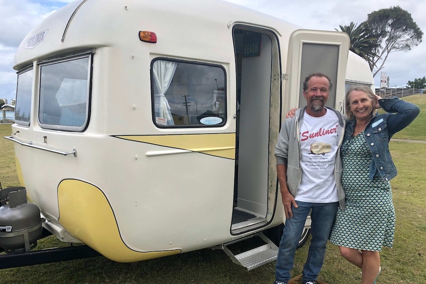 Walter and Adrienne Hacene standing arm in arm outside one of their three Sunliner caravan at the 60th Anniversary in Forster