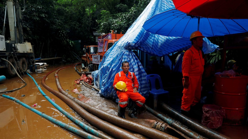 A rescue worker waits by pumps and lots of water at the operation to free 12 Thai boys and their soccer coach from a cave system