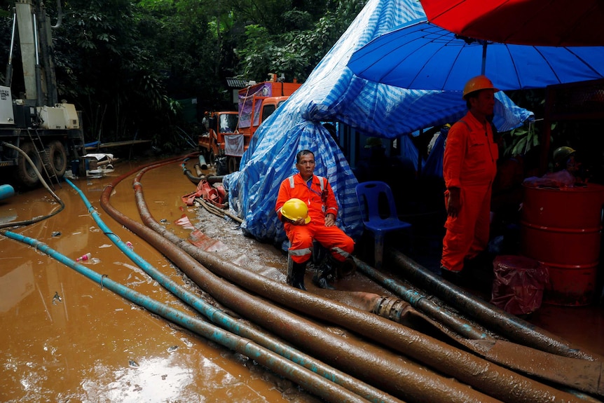 A rescue worker waits by pumps and lots of water at the operation to free 12 Thai boys and their soccer coach from a cave system