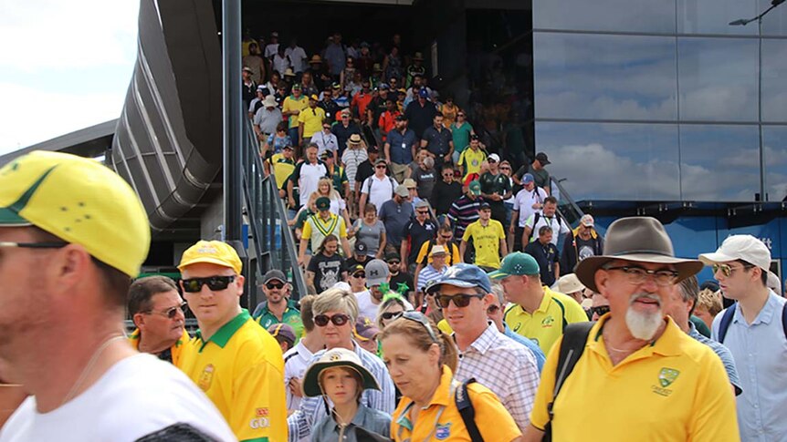 Cricket fans stream down a packed staircase at teh Stadium Train station.