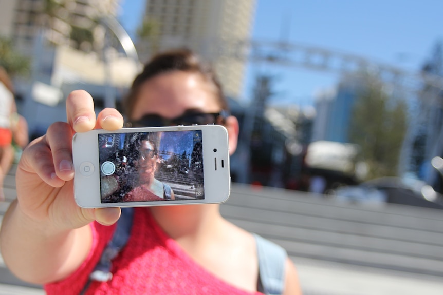 A tourist takes a selfie with their smartphone at the popular Surfers Paradise sign on the Gold Coast.