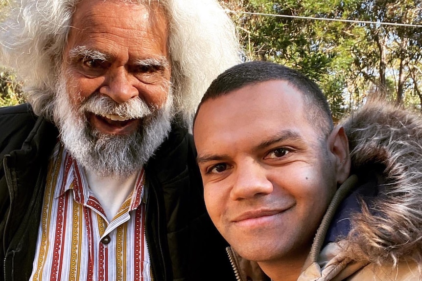 An elderly man and young man take a selfie.