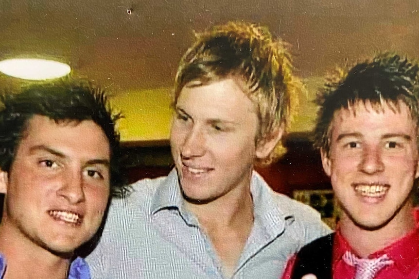 Bryce Farrell with arms around two friends at a social function