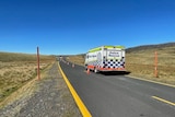 A police van on a highway in the snowy mountains