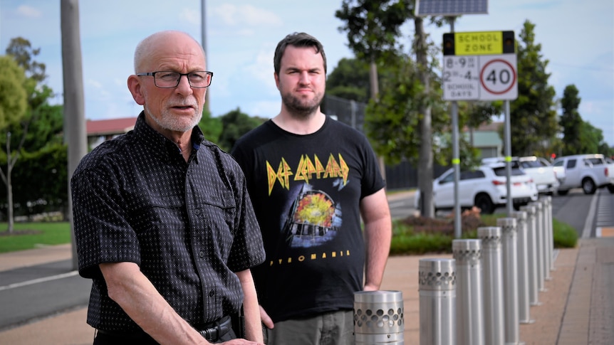 Two men next to a 'School Zone' sign