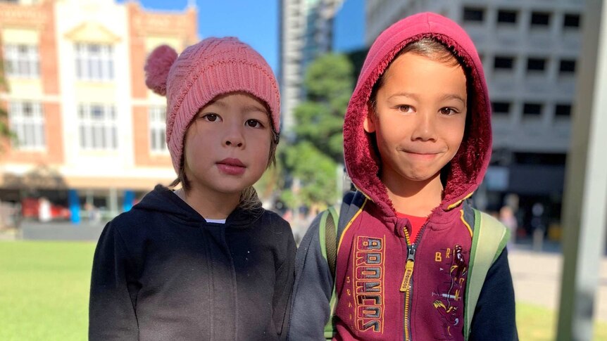 Young boy and girl wearing jumpers and beanies in the city.