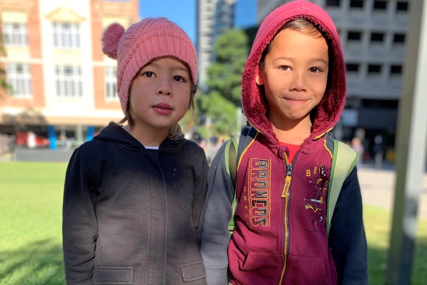 Young boy and girl wearing jumpers and beanies in the city.